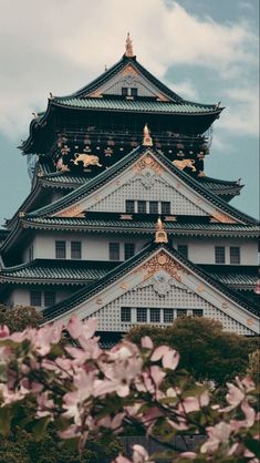 the top of a building with flowers in front of it and blue sky behind it