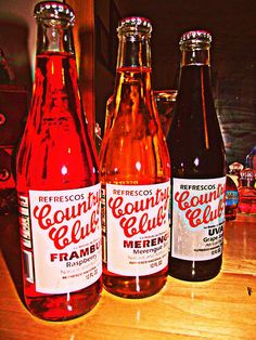 three different flavored sodas sitting on top of a wooden table