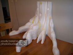 a large white sculpture sitting on top of a wooden table next to a chair and wall