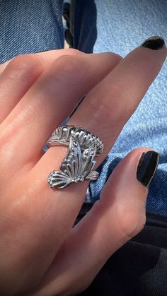 a woman's hand with a ring on top of her finger and black nail polish