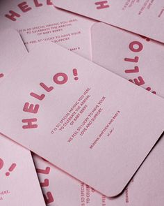 pink business cards with the word hello written on them are stacked in close proximity to each other