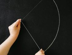 someone is making a necklace with silver chains on a black surface and holding the string in their hand