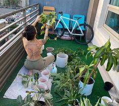 a woman sitting on top of a balcony next to potted plants