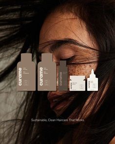 a woman's face with her hair blowing in the wind and three bottles of cleanser