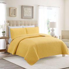 a bed with yellow bedspread and pillows in a room