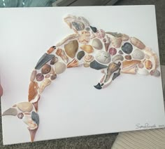 a person holding up a piece of art made out of seashells and shells