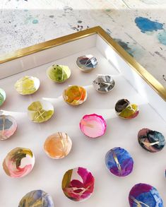 an assortment of colorful painted buttons in a white box