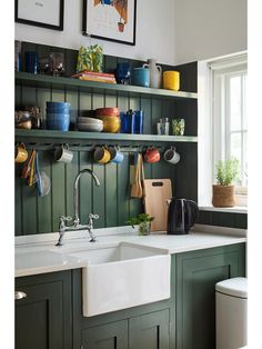 a kitchen with green painted cabinets and white sink, hanging pots and pans on the wall