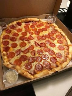 a large pepperoni pizza in a box on a table