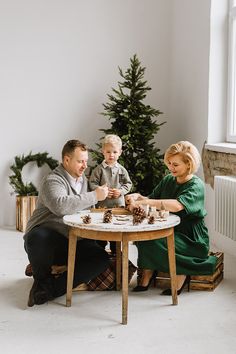 a man, woman and child sitting at a table with christmas decorations