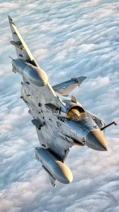 a fighter jet flying through the sky above some white clouds and blue sky with yellow highlights