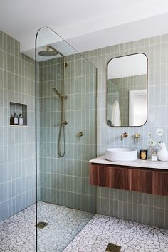 a bathroom with a walk in shower next to a white sink and wooden counter top