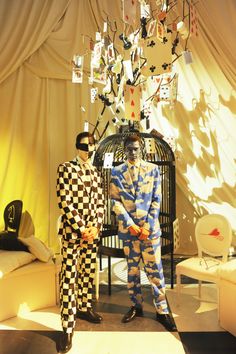 two mannequins dressed in checkered suits stand next to a bird cage