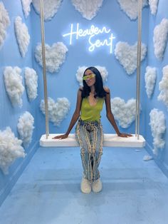 a woman standing in front of a blue wall with clouds on it and the words heaven sent above her