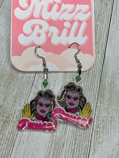 two earrings with pink and yellow designs on them sitting next to a sign that says mozzy bril