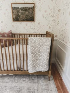 a baby's crib in the corner of a room with floral wallpaper