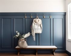 a hat, coat rack and bench in a room with blue paneling on the walls