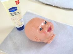 a baby doll head sitting next to a tube of toothpaste on a table