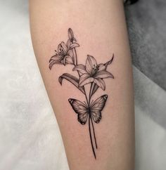 a black and white photo of flowers with butterflies on the arm, done by tattoo artist person