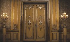 an ornate gold door with chandeliers on either side