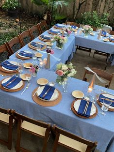 a table set with blue linens and place settings for an outdoor dinner or party