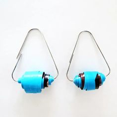 two small blue objects hanging from metal hooks on a white surface, one is shaped like a cone and the other is shaped like a rectangle