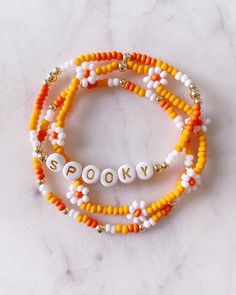 three beaded bracelets with the word sorry written on them in white, orange and yellow beads