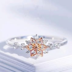 a white and pink diamond ring sitting on top of a book