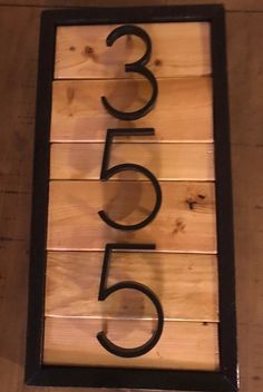 a wooden sign with the number five in black on it's front and bottom