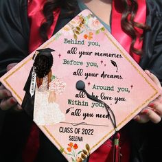 a woman holding a pink graduation cap with writing on it