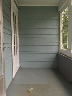 an empty porch with no furniture on the floor and one door open to another room