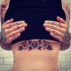 a woman with tattoos on her stomach holding her hands behind her back and looking at the camera