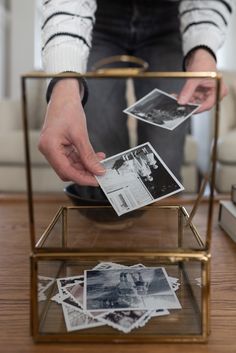 a person is holding photos in a glass box on a table with books and other items