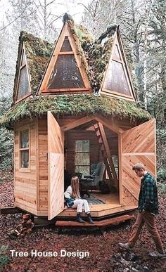 a man and two children are sitting in a tiny house with moss growing on the roof