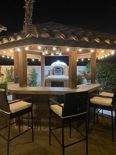 an outdoor kitchen with lights on the roof and grill area in the background at night