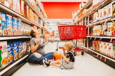 a woman and child sitting on the floor in a grocery store aisle next to each other