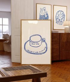 there is a coffee cup on the table in front of two framed pictures and a wooden bench