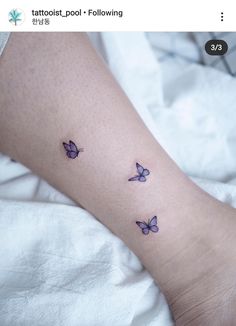 a woman's foot with three purple butterflies on the left side of her leg