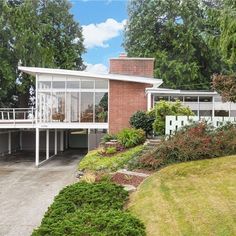 the house is surrounded by lush green trees and shrubs, with an overhanging balcony