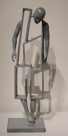 a sculpture of a man standing in front of a white wall and holding onto a piece of metal