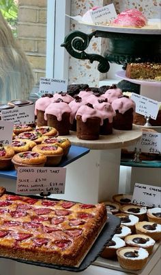 many different types of pastries on display in a store window, including pies and cupcakes