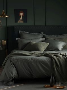 a bedroom with dark green walls and bed linens on the floor, along with two side tables