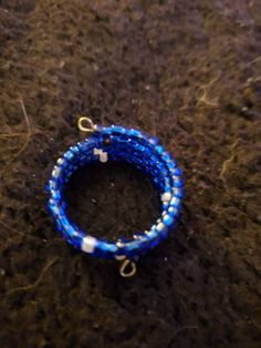 a blue and white beaded bracelet sitting on top of a brown table next to a pair of scissors