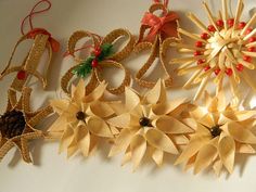 four different types of paper flowers on a white surface with red and green ribbons hanging from them