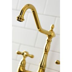 a gold faucet in a bathroom with white tiles on the wall behind it