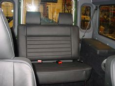 the interior of a vehicle with black leather seats and gray walls, including two windows