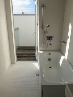 a bathroom with a white bath tub sitting next to a shower head and hand rail