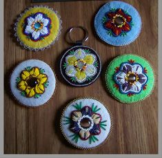 six embroidered flowers are displayed on a wooden surface with a keychain in the foreground