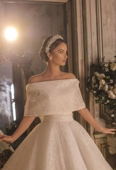 a woman in a white wedding dress standing next to a mirror