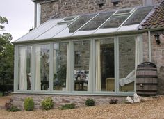 a stone house with a glass roof and large windows on the side of the house